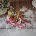 Load image into Gallery viewer, Teddy bear on a red sled with Christmas decorations in a snowy scene
