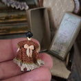 Load image into Gallery viewer, Small crocheted dress on a tiny doll held in a hand with a blurred background
