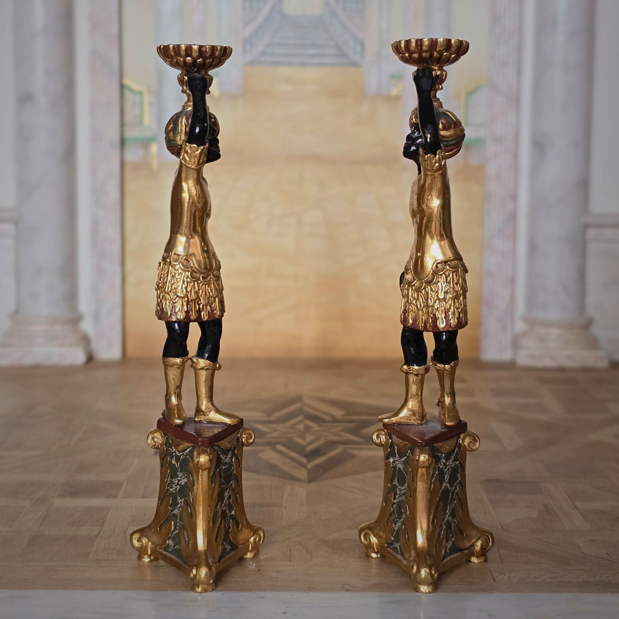 Pair of ornate gold and black pedestal stands in a classical setting by John J. Hodgson
