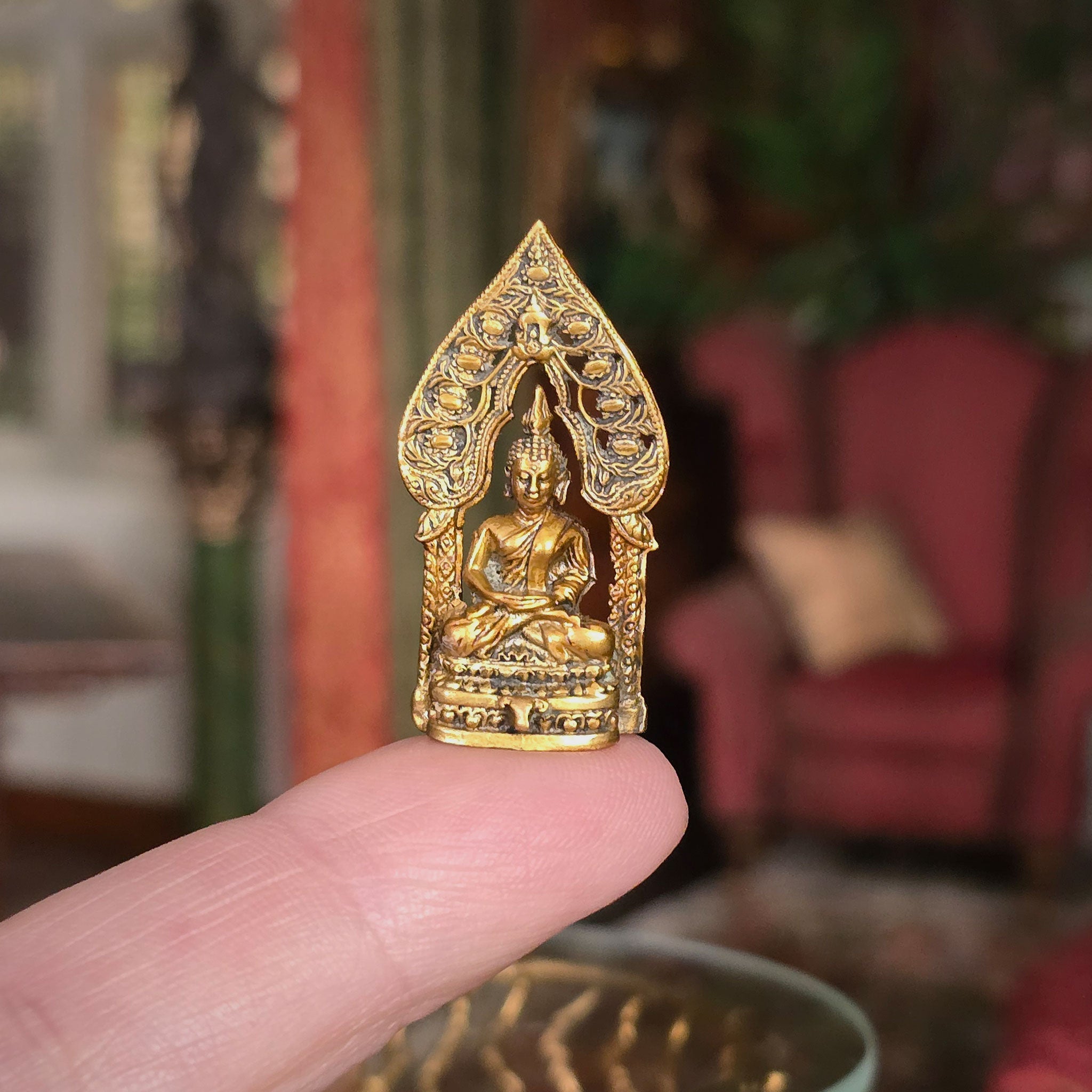 Gold Buddha statue held in a hand with a blurred indoor background