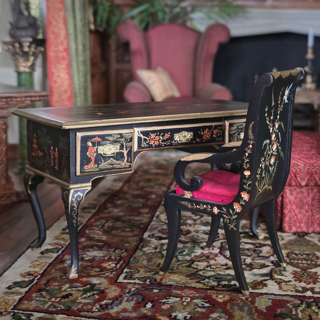 Decorative desk and chair with intricate designs in a room with a fireplace and pink armchair.