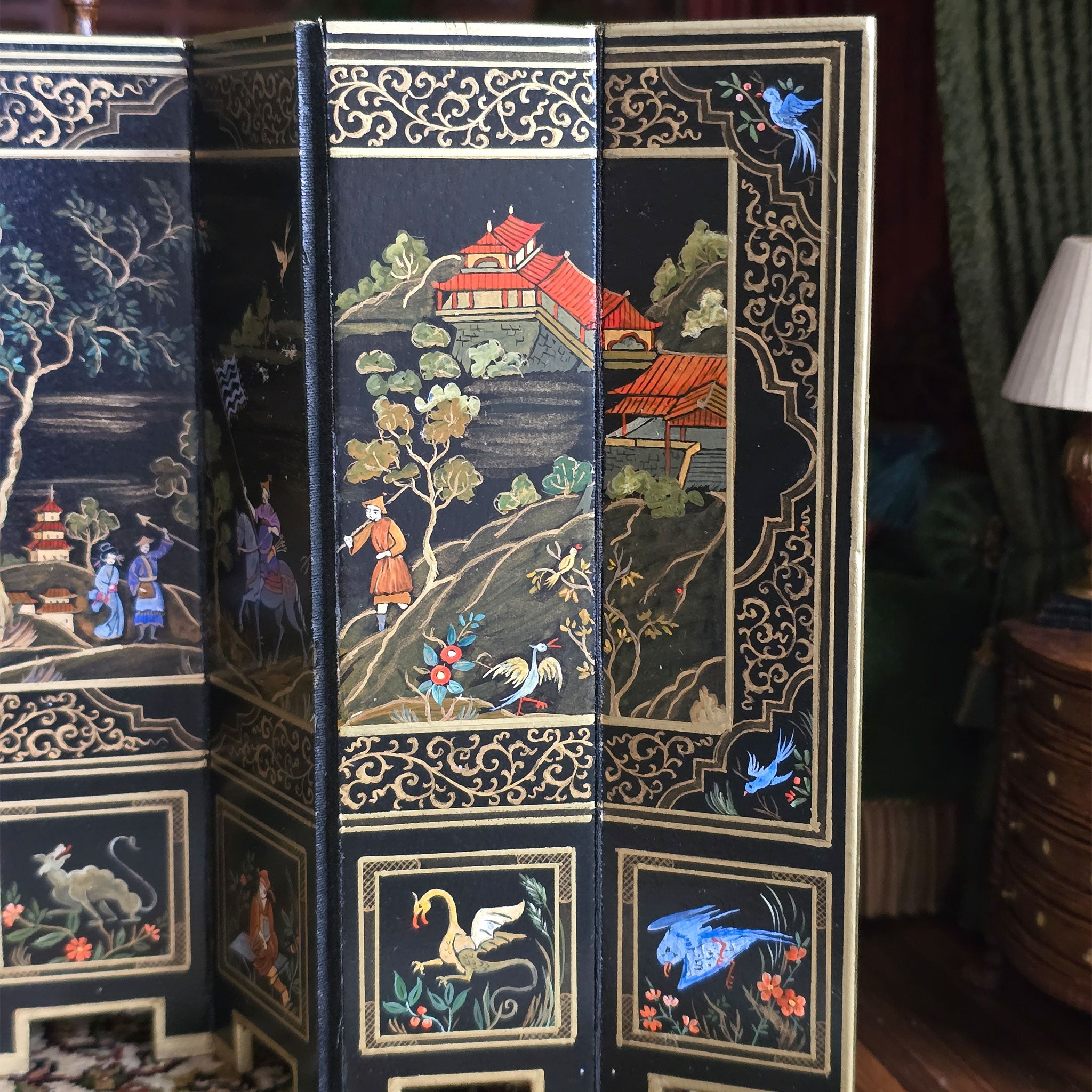 Decorative book with intricate designs of landscapes and figures on a room divider.