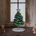 Load image into Gallery viewer, Decorative Christmas tree figurine with a star on top, surrounded by small teddy bears, in a room with wooden floor and window.
