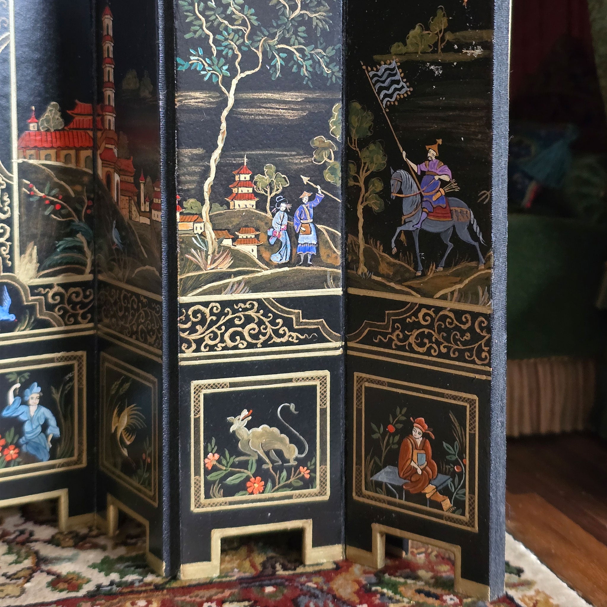 Decorative folding screen with intricate scenes and patterns on a wooden floor screen.