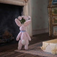 Load image into Gallery viewer, Pink plush bunny with a bow tie standing near a fireplace in the background.
