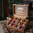 Load image into Gallery viewer, Wooden box with colorful Christmas ornaments on a patterned rug
