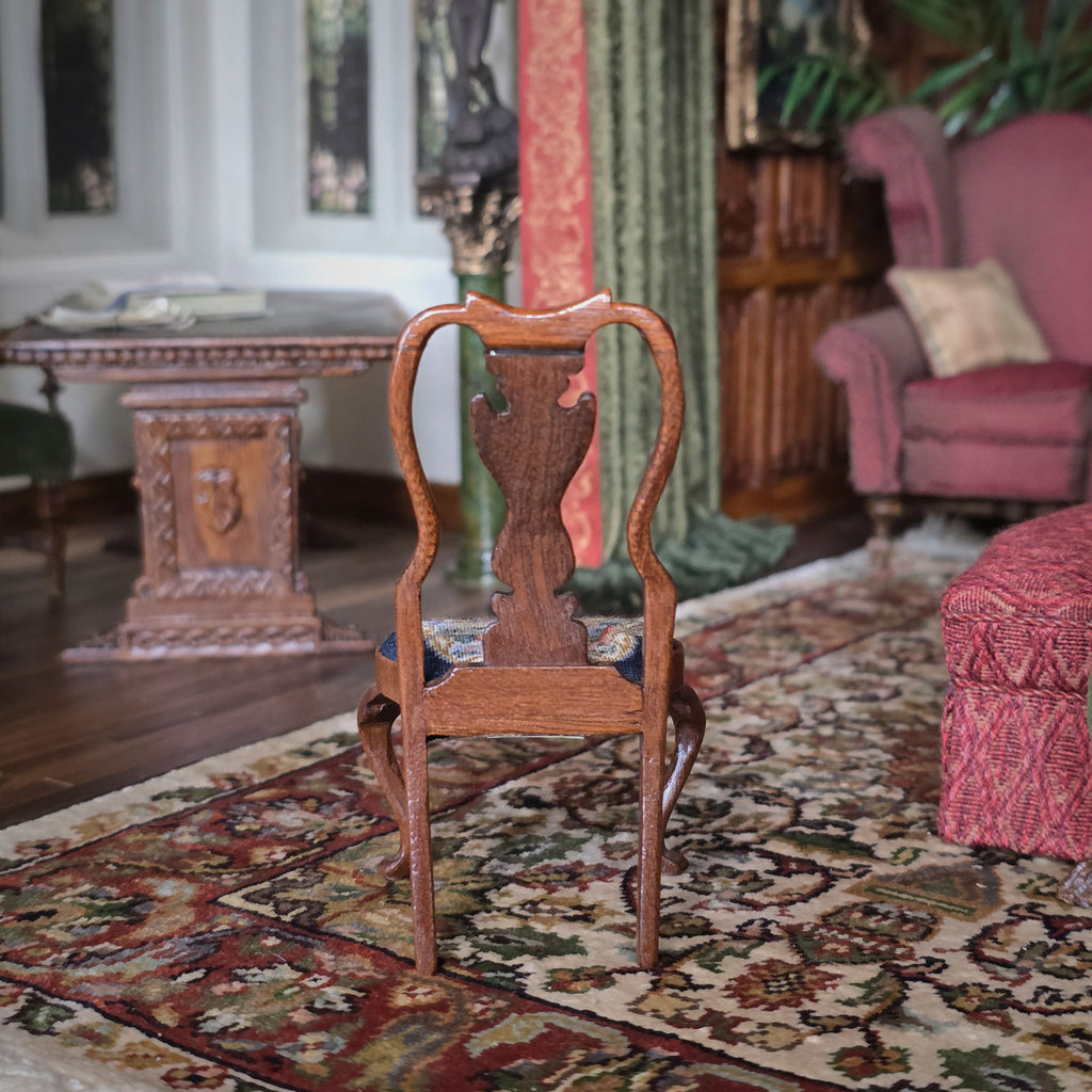 Backside of a wooden chair on a patterned rug with a blurred background of a room with furniture.
