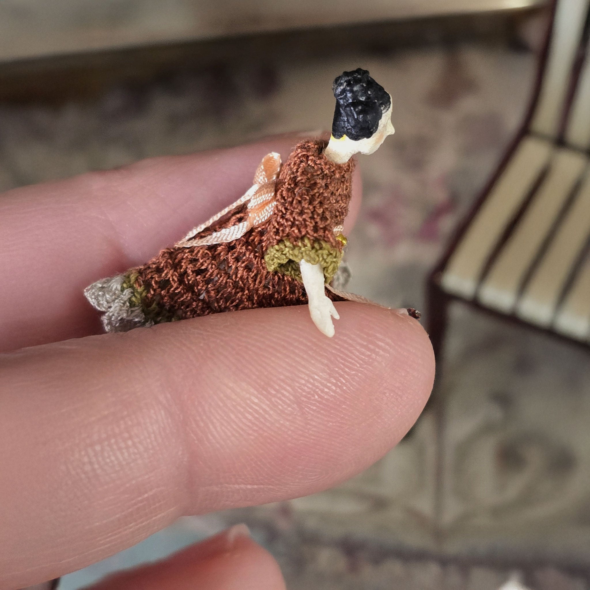 Small porcelain doll held between fingers, close up