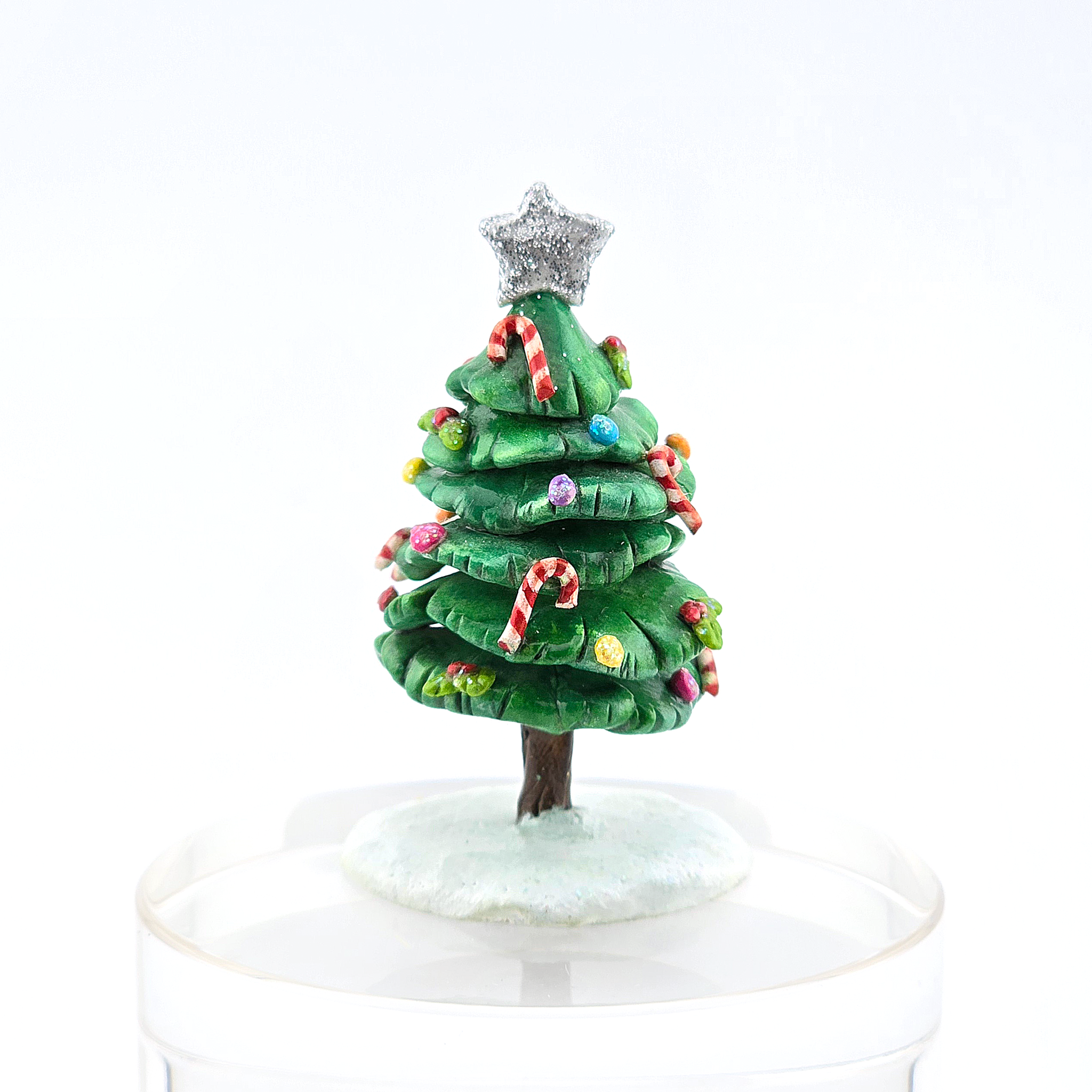 Small green Christmas tree figurine with colorful decorations and a silver star on a white background