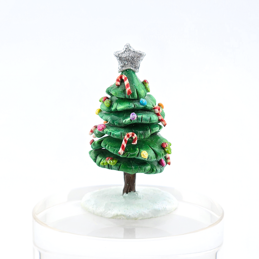 Small green Christmas tree figurine with colorful decorations and a silver star on a white background