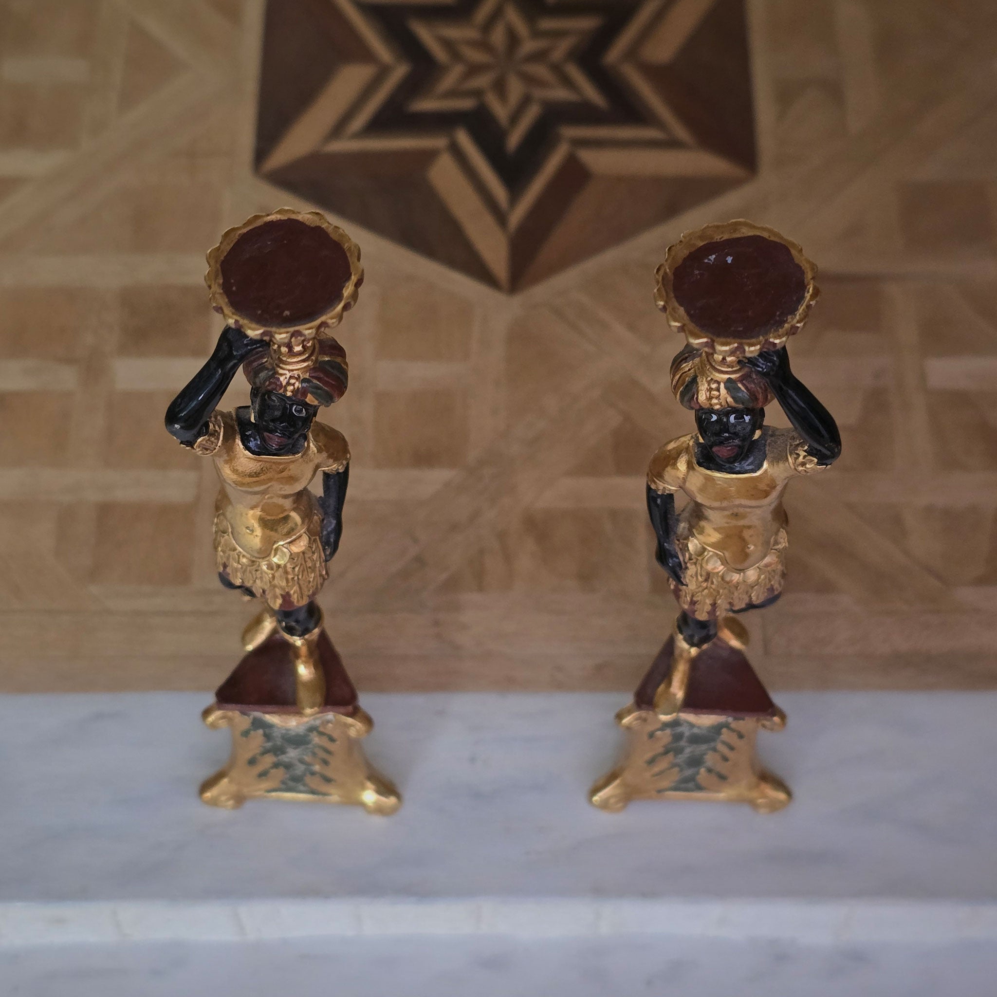 Top view of two ornate pedestal figures on a marble surface 