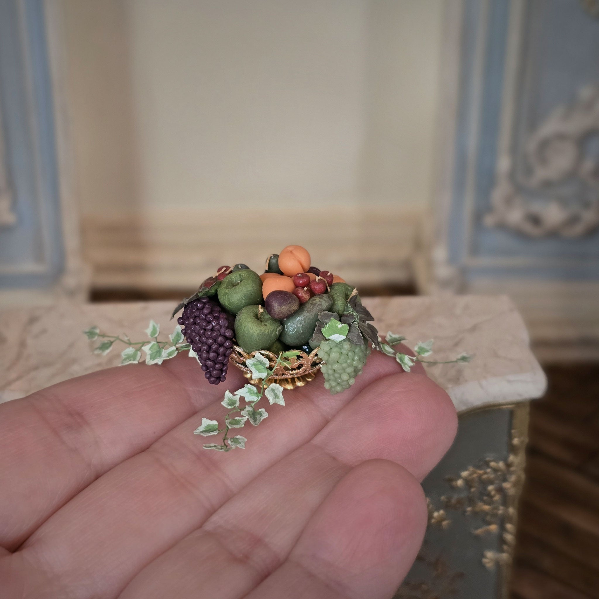 Miniature fruit and berry centerpiece arrangement held in a hand with a blurred background