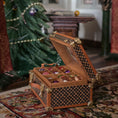 Load image into Gallery viewer, Wooden Christmas box with decorative patterns on a patterned rug, with a Christmas tree in the background.
