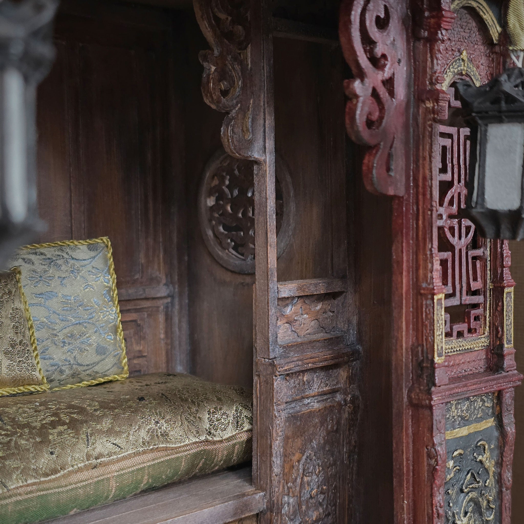 Decorative wooden bench area with intricate carvings and a patterned cushion in a carved alcove