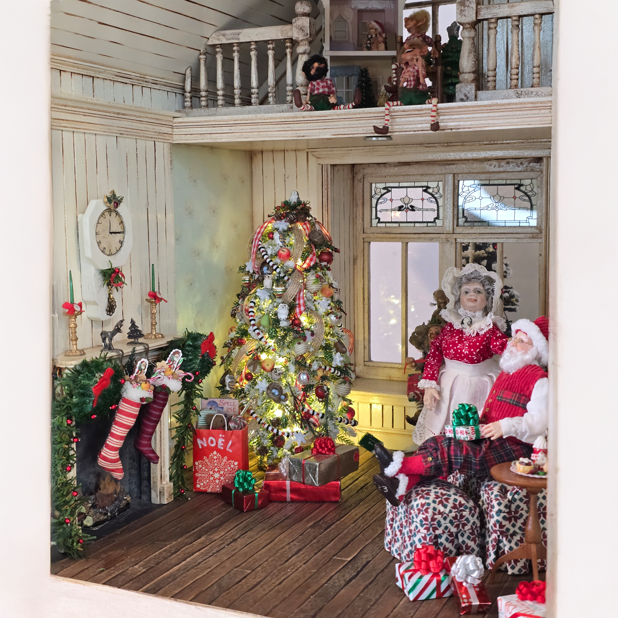 Decorative Christmas scene with a tree, Santa Claus, and stockings in a small house.