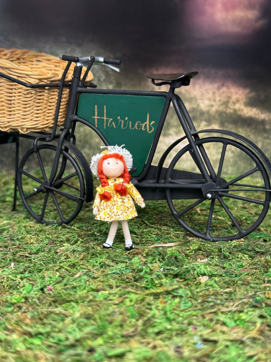 Ann Anderson Little Red Head Toy Dolly in Yellow Spring Dress, standing in front of a bicycle