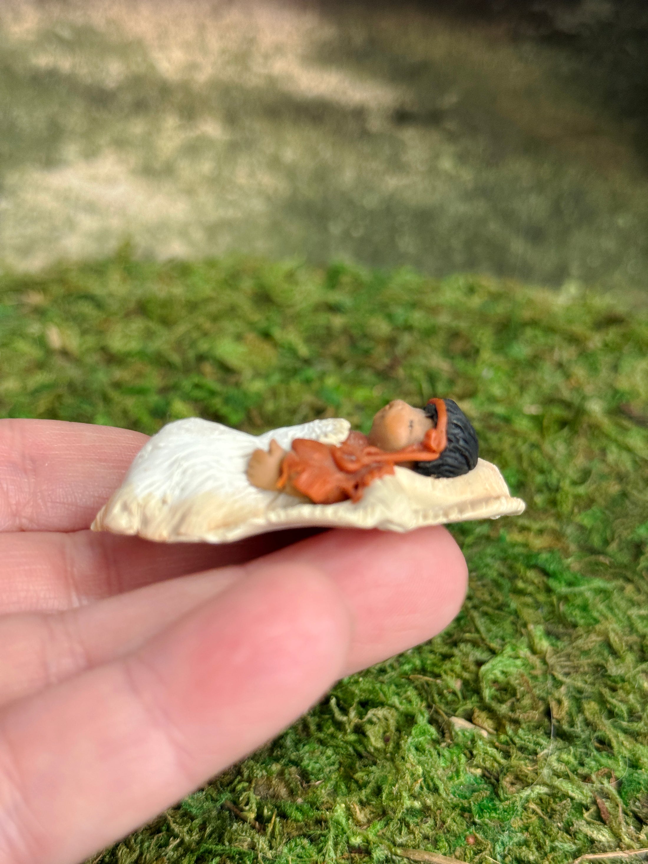 Signed Sculpted Clay Sleeping Native American Baby Doll Figurine, laying in a hand, left side view