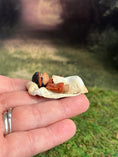Load image into Gallery viewer, Signed Sculpted Clay Sleeping Native American Baby Doll Figurine, laying in a hand, right side view
