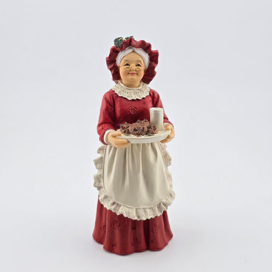 Mrs. Claus doll in a red dress and bonnet holding a plate with a cup on a white background