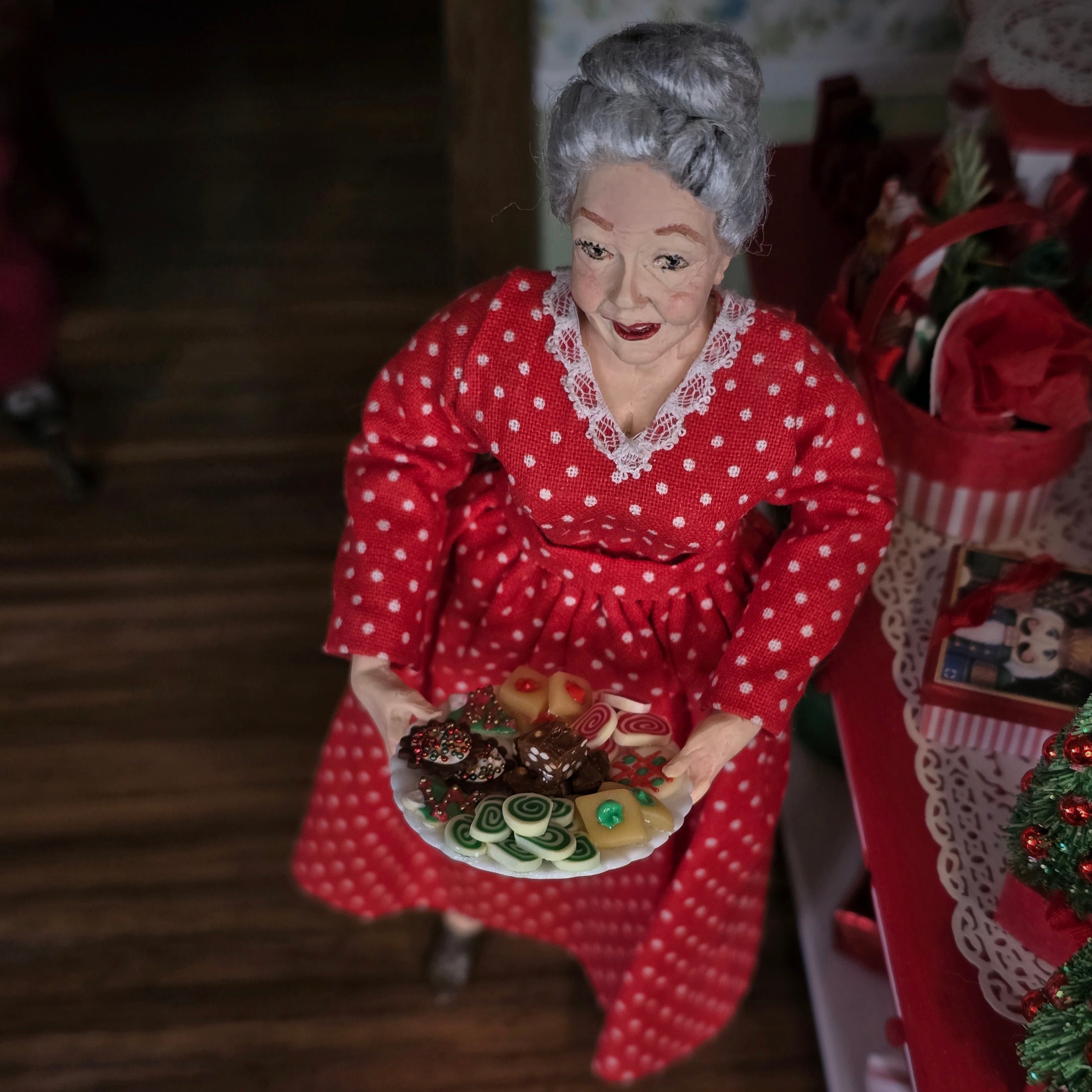 Decorative figure of an elderly woman in a red polka dot dress holding a plate of cookies.