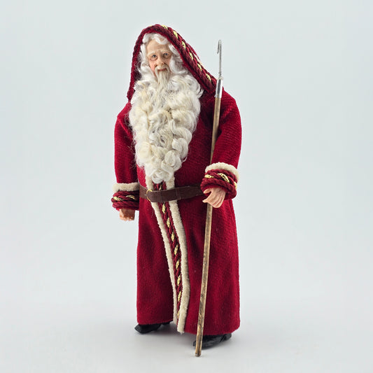 Santa Claus doll in a red robe with a white beard and staff on a white background