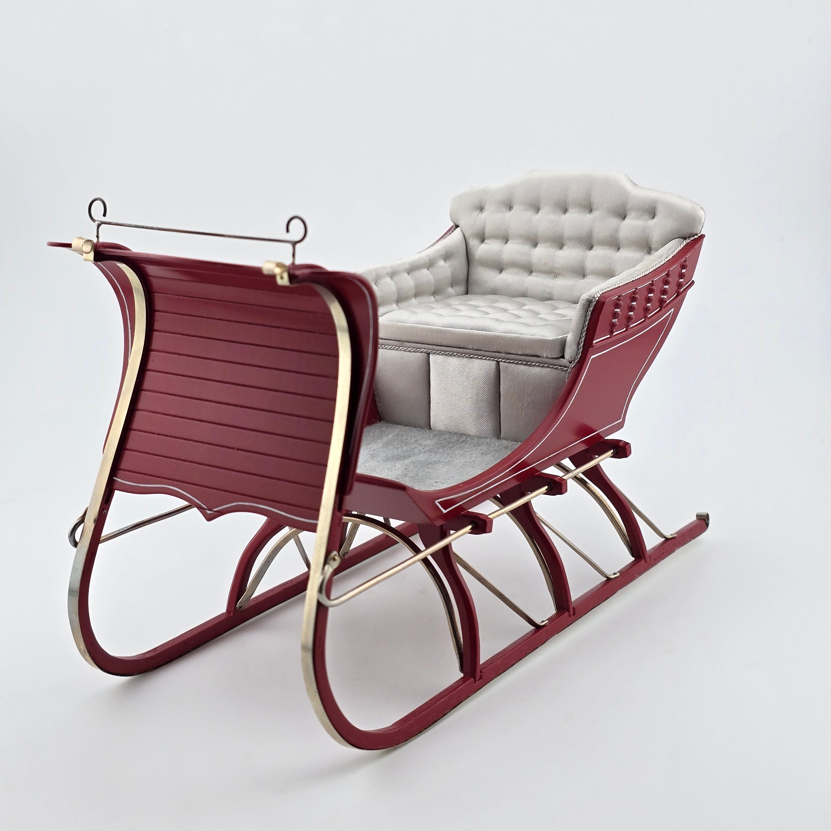 red sleigh with white cushioned seat on a white background