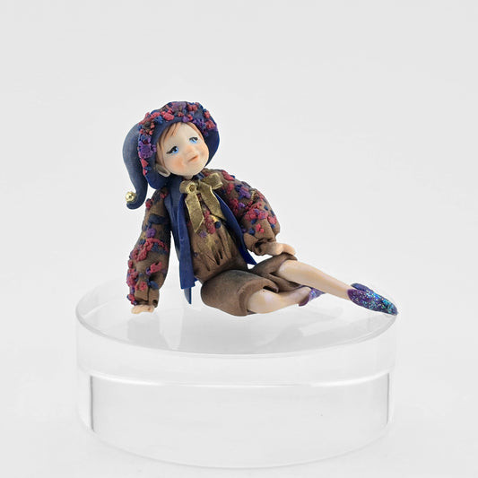 Sculpted clay elf boy doll wearing a purple outfit on a white background
