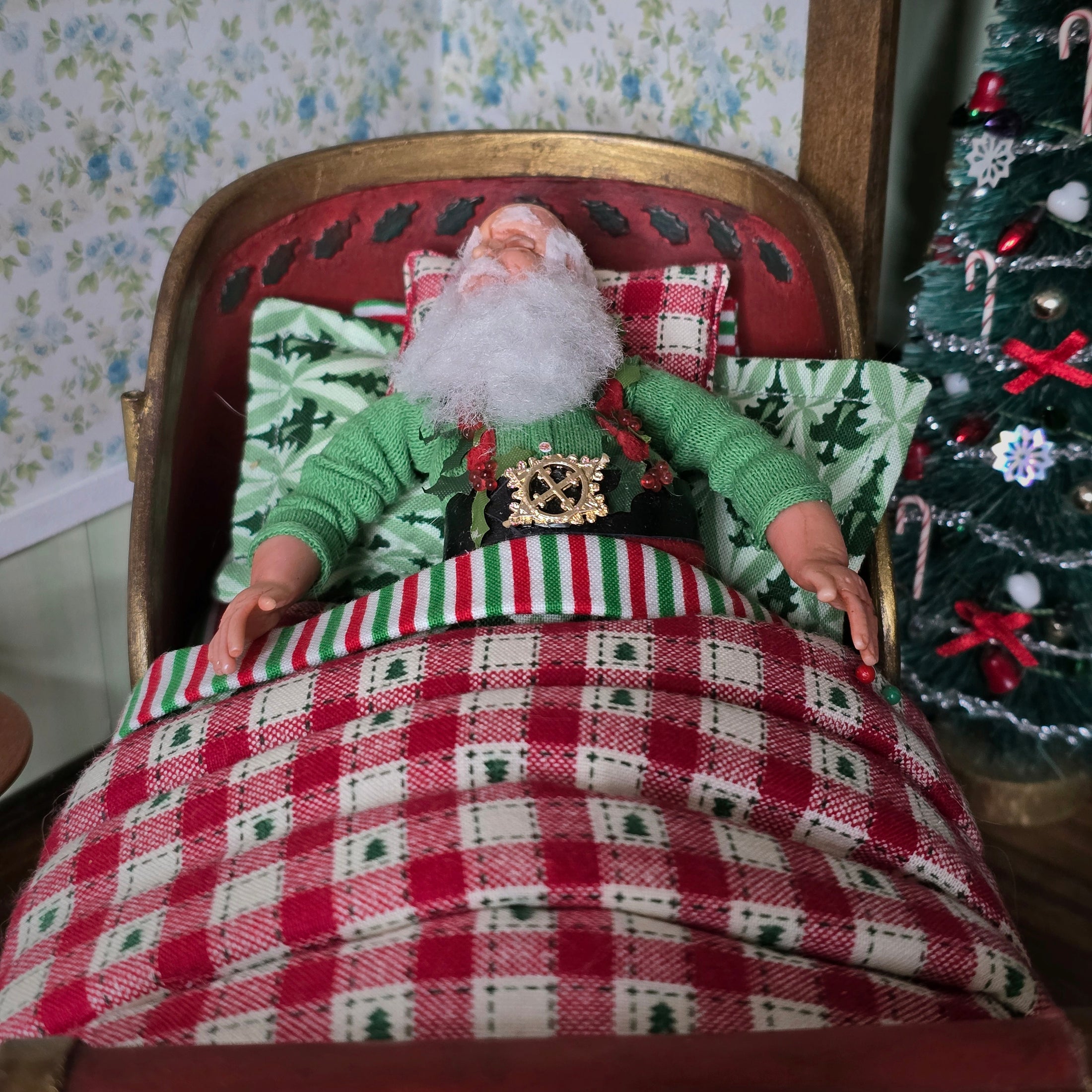 Santa Claus doll lying in a bed with a Christmas tree in the background