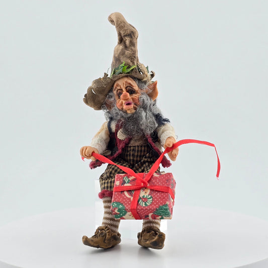 Decorative elf doll holding a gift box on a white background