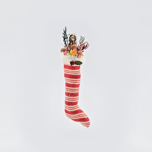 Decorative miniature dollhouse Christmas stocking with red and white stripes on a white background