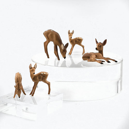 Set of deer figurines on a clear stand against a white background