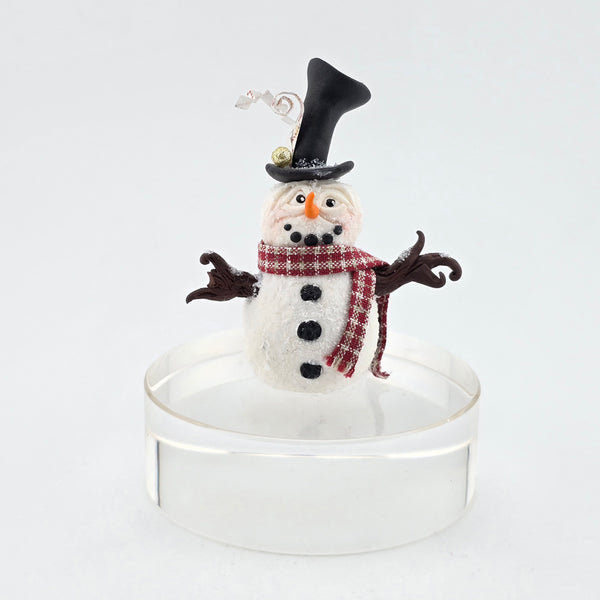 Decorative snowman miniature with a top hat and scarf on a white background