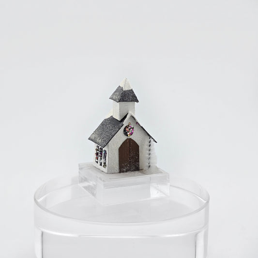 Small model of a church on a clear stand against a white background