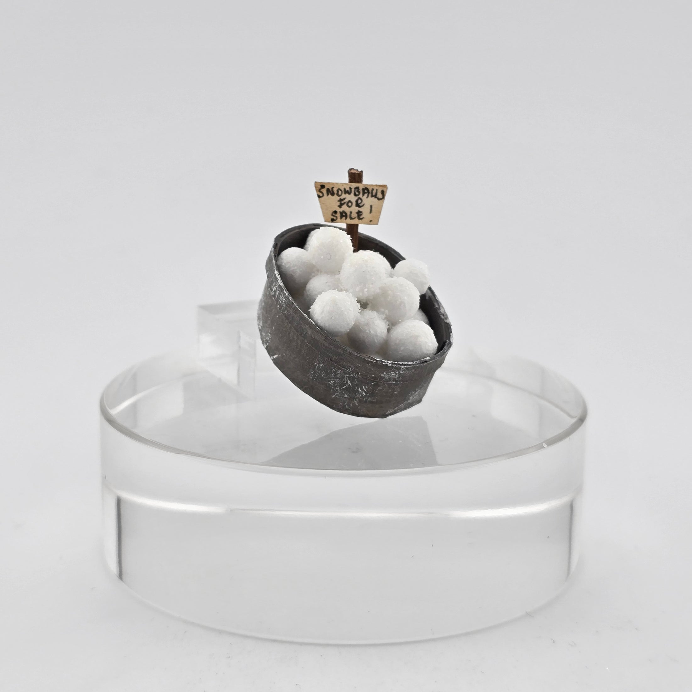 Decorative snowball display with a sign on a clear stand against a white background