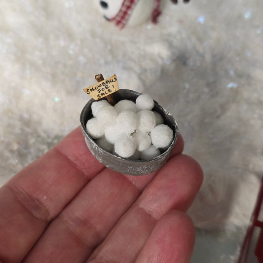 Small bowl filled with white balls held by a hand, with a blurred background