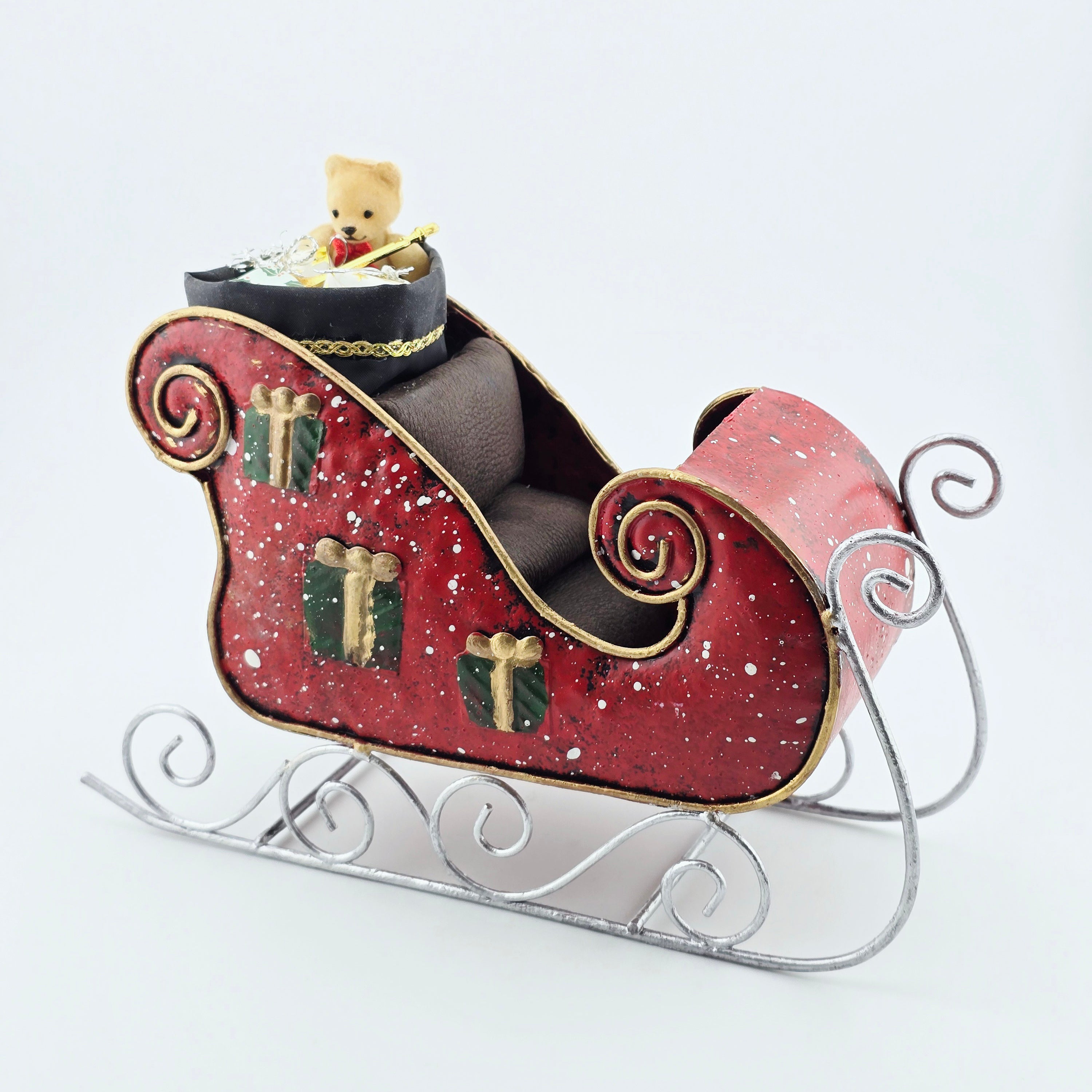 Decorative sleigh with a teddy bear and presents on a white background