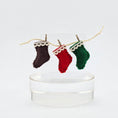 Load image into Gallery viewer, Three miniature wool stockings in brown, red, and green hanging on a string against a white background.
