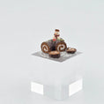 Load image into Gallery viewer, Chocolate roll cake with a snowman decoration on a white cube platform

