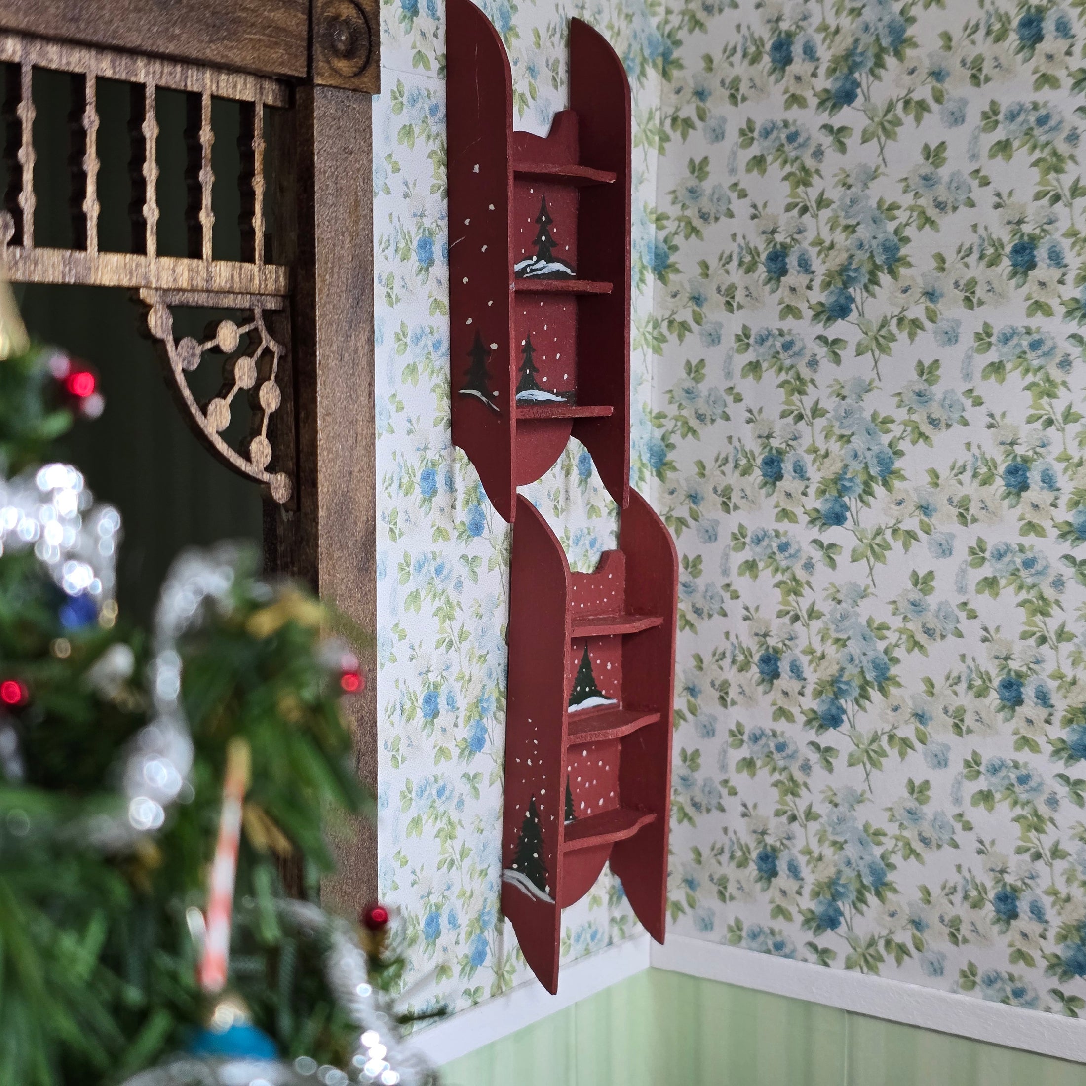 Red wall shelf with decorative items against a floral wallpapered wall.