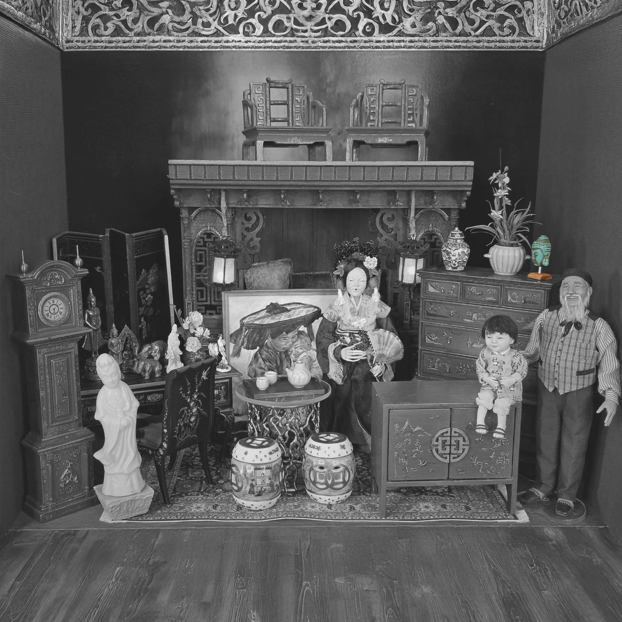 Black and white photograph of a detailed dollhouse interior with furniture and decorative items.