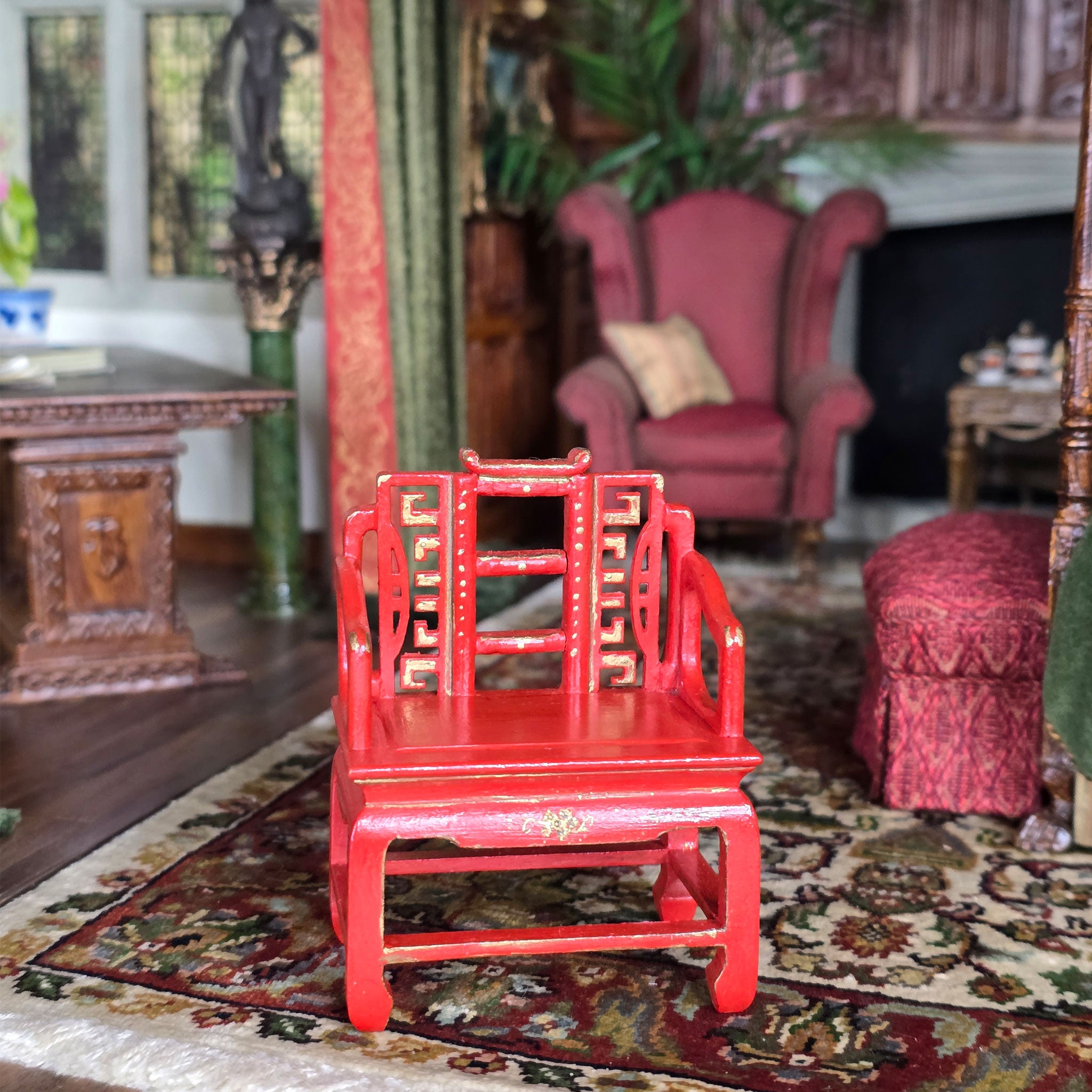 Red oriental chair in a decorated room with a fireplace and ornate furniture.