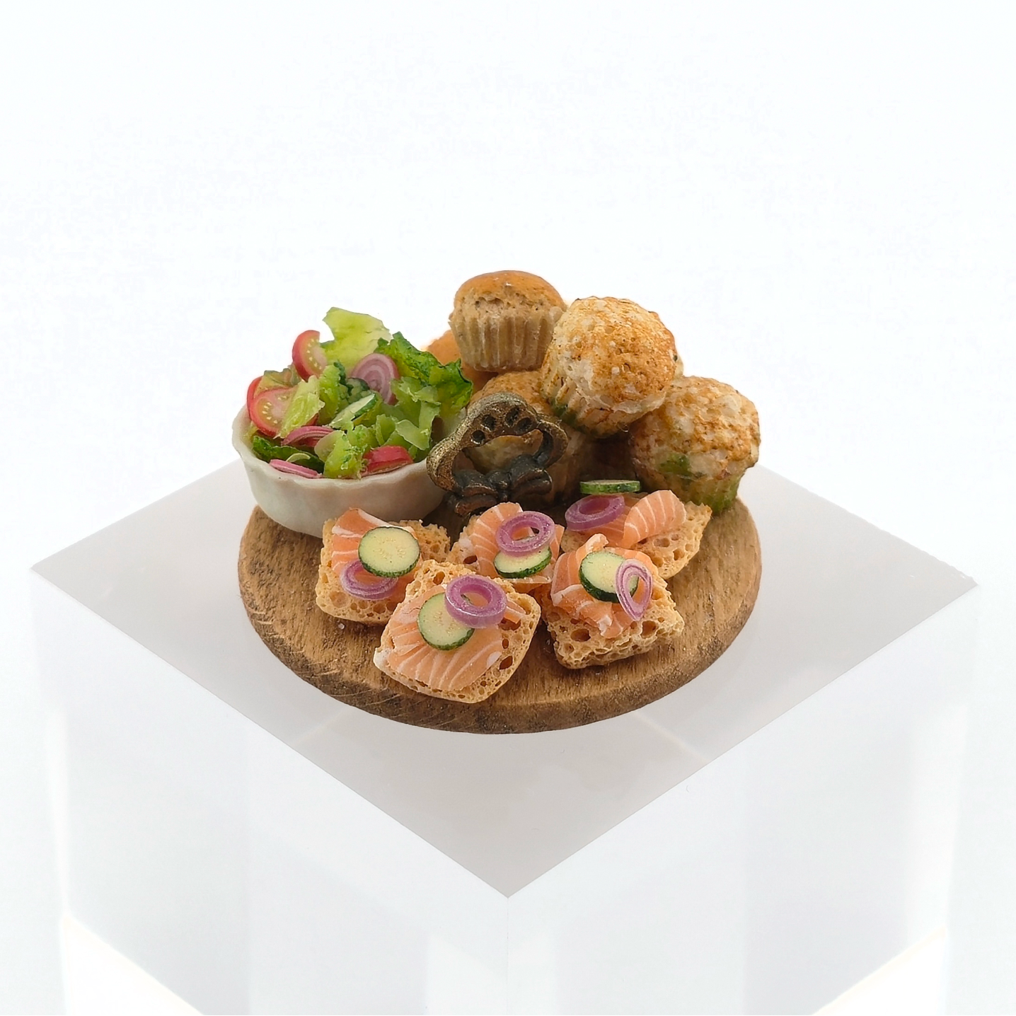 Assorted finger foods including a bowl of salad, bread slices with pickles, and pastries on a white background.