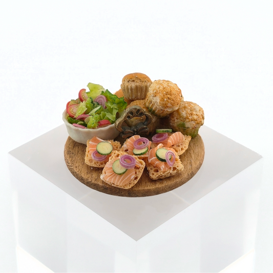 Assorted finger foods including a bowl of salad, bread slices with pickles, and pastries on a white background.