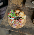 Load image into Gallery viewer, Assorted finger foods including a bowl of salad, muffins, and pastries on a wooden board.
