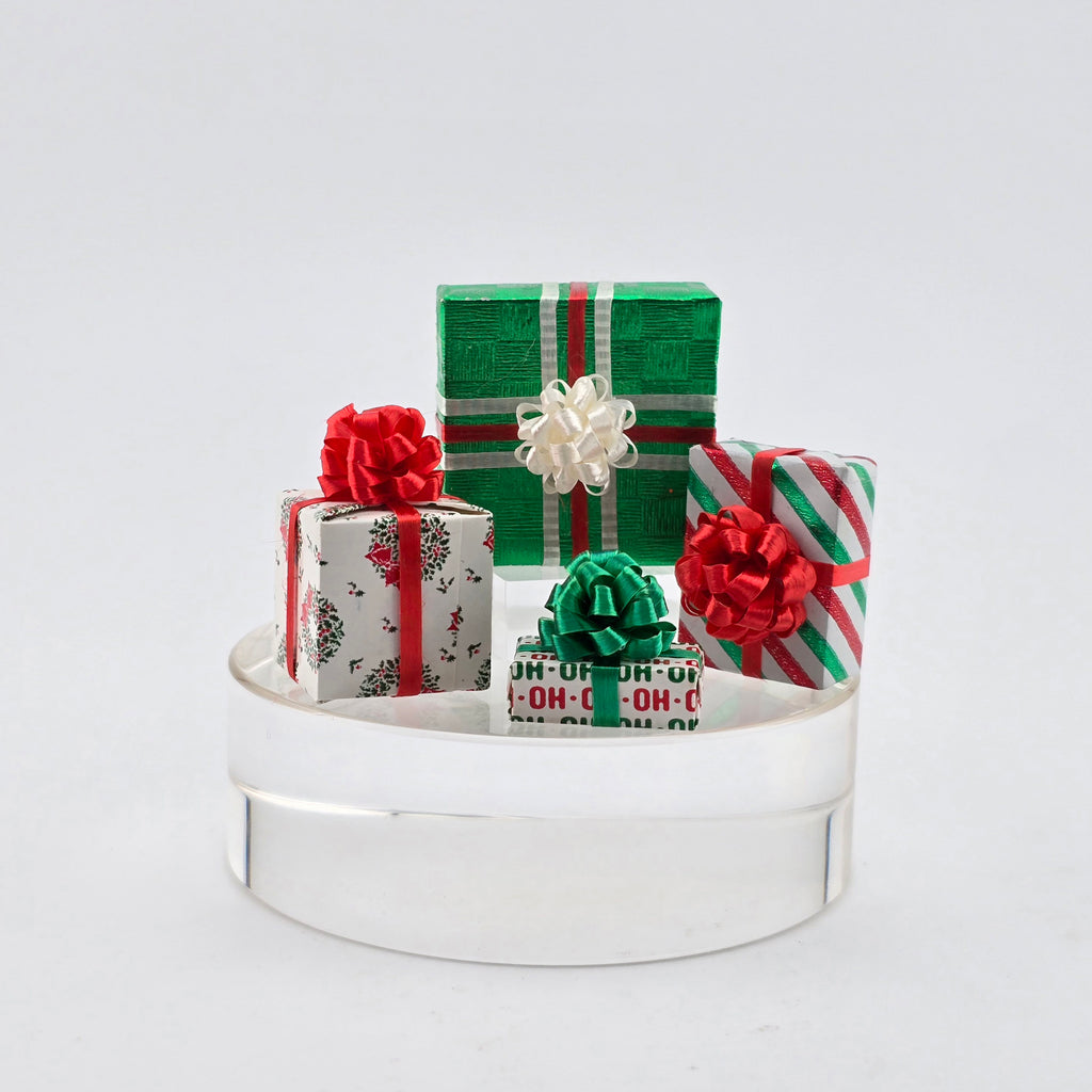 Decorative arrangement of small gift boxes on a white stand with a light gray background