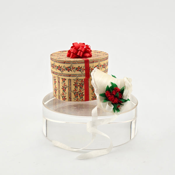 miniature dollhouse hat box with floral hat on a white background