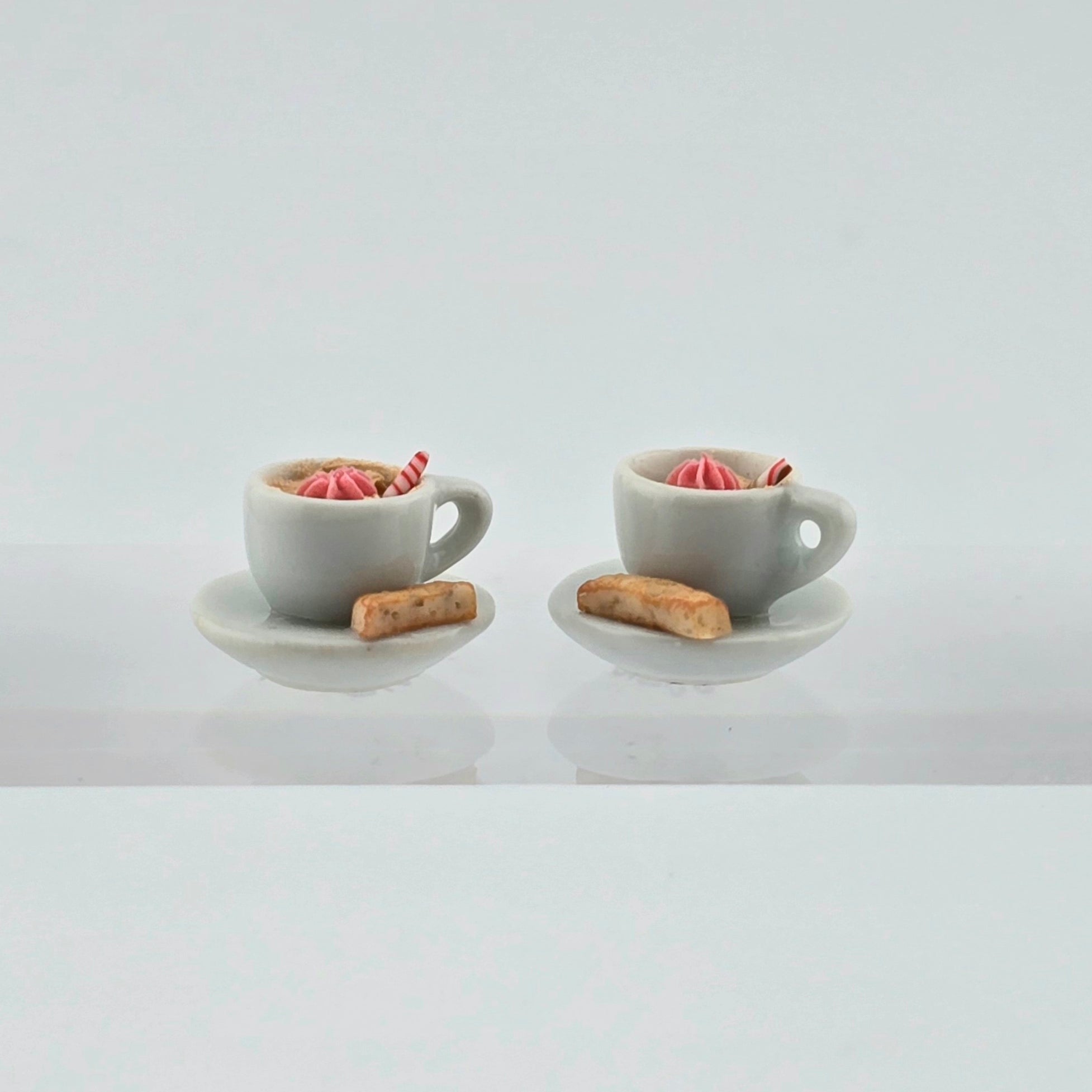 Pair of miniature hot cocoa cups with cream and biscotti