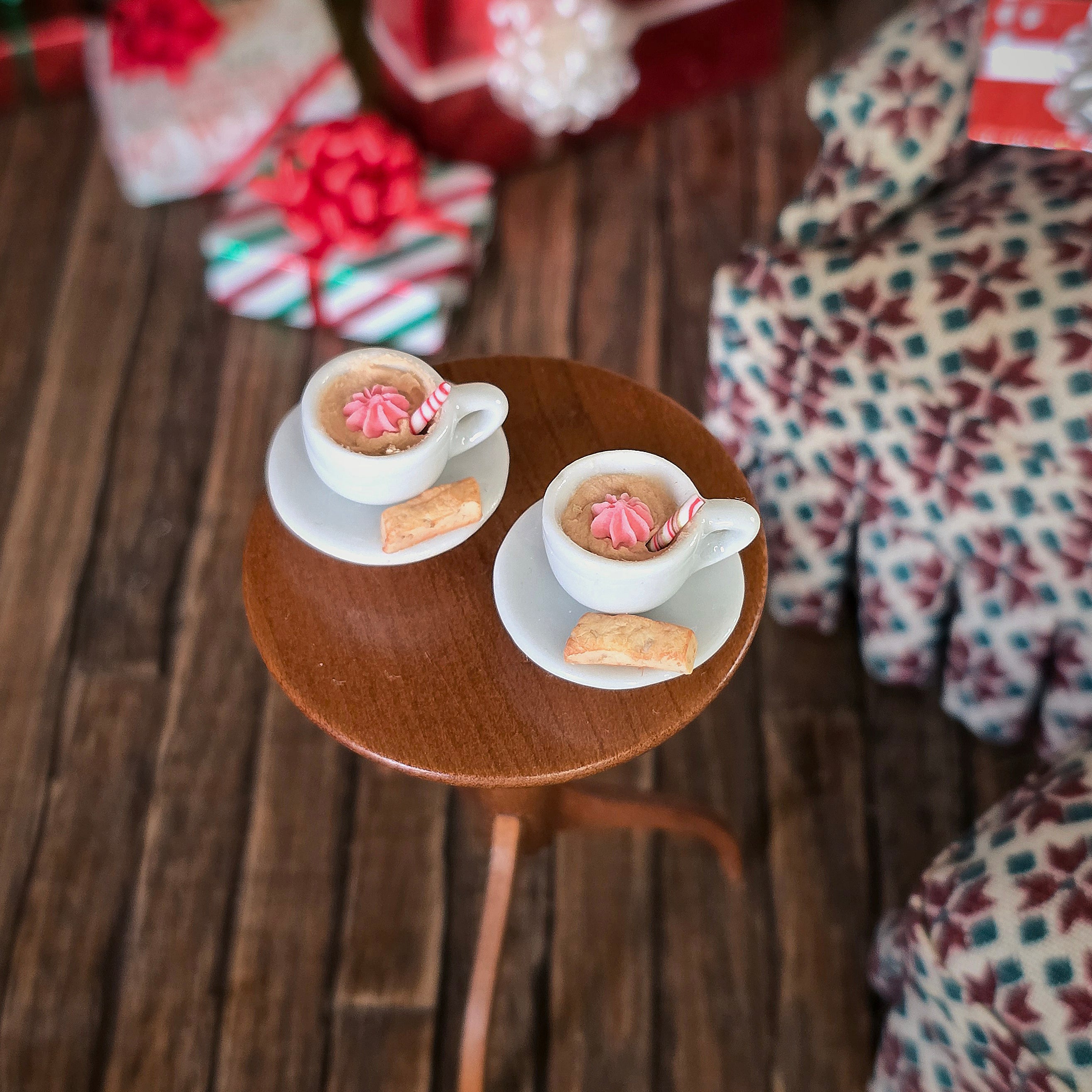 Pair of miniature hot cocoa cups with cream and biscotti, on small table