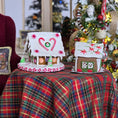 Load image into Gallery viewer, Decorative gingerbread houses on a plaid tablecloth with Christmas trees in the background
