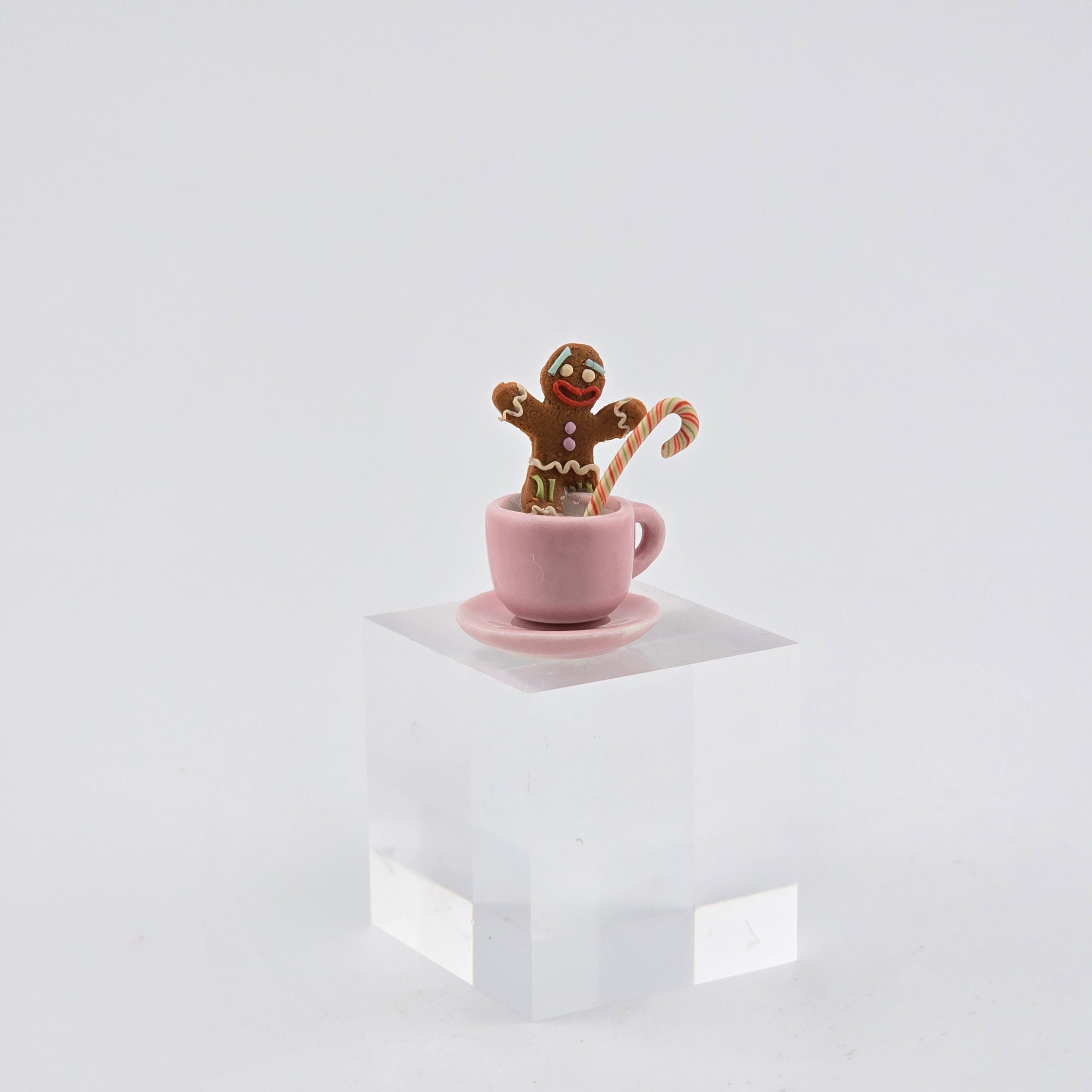 Gingerbread man in a pink cup with a candy cane on a white background